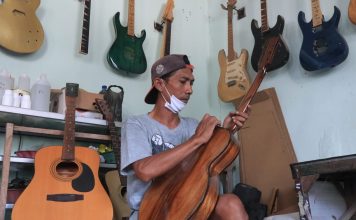 Berawal Hobi Musik, Pria di Jombang Jadi Perajin Gitar Elektrik Muhammad Andik Gunawan melakukan proses finishing gitar elektrik di Dusun Ngundo, Desa Candimulyo, Kecamatan/Kabupaten Jombang. IM.com/Karimatul Maslahah/
