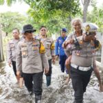 Kasatlantas Polres Kota Mojokerto, AKP Mulyani mengendong warga terdampak banjir.