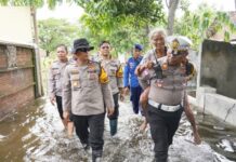 Kasatlantas Polres Kota Mojokerto, AKP Mulyani mengendong warga terdampak banjir.