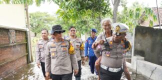 Kasatlantas Polres Kota Mojokerto, AKP Mulyani mengendong warga terdampak banjir.