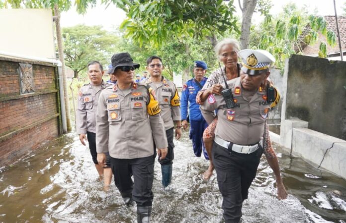 Kasatlantas Polres Kota Mojokerto, AKP Mulyani mengendong warga terdampak banjir.