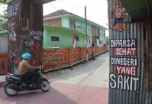 Ketua RT 25 Kedungmaling, Muhammad Basuki saat menunjukkan gapura seng berkarat./Karimatul Maslahah/
