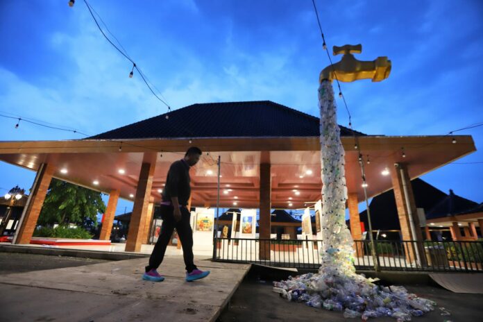 Instalasi berbentuk keran air raksasa setinggi tiga meter karya Ecoton, simbol kritik terhadap bahaya konsumsi makanan dan minuman dalam kemasan plastik.