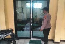Petugas kepolisian melakukan olah TKP di balai Desa Buncitan Sedati Sidoarjo terkait temuan kepala desa meninggal dunia