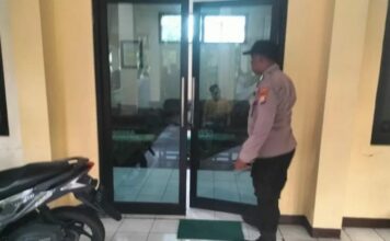 Petugas kepolisian melakukan olah TKP di balai Desa Buncitan Sedati Sidoarjo terkait temuan kepala desa meninggal dunia